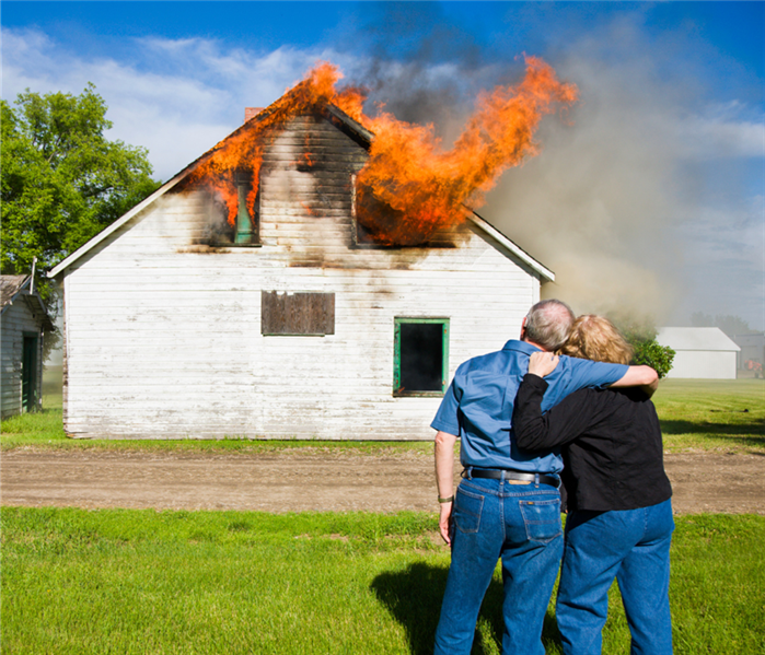 couple standing in front of burning house